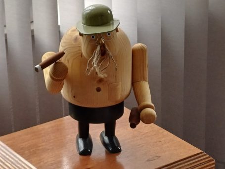 Houten man met groene helm, sigaar en zwarte schoenen